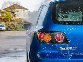 Pressure washing blue Mazda car