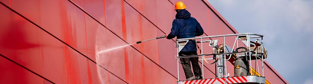 Professional pressure washing tall red commercial building