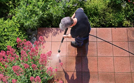 Professional pressure washing red concrete tile patio