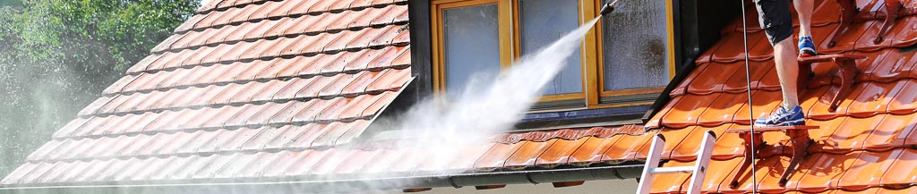 Worker pressure washing orange roof