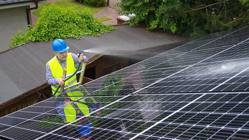 Worker spraying black solar panels